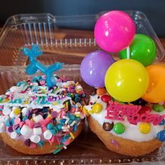 two donuts decorated with balloons and confetti on a tray next to each other