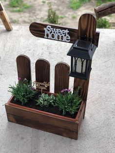 a small wooden box with plants and a light on it that says sweet home in the center