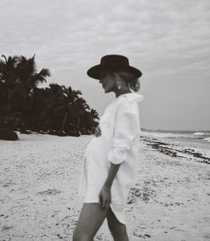 black and white photograph of woman walking on beach with palm trees in the back ground