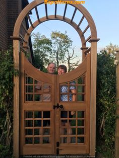 two people standing in front of a wooden gate with latticed design on the top