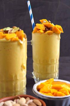 two glasses filled with fruit and nuts on top of a table next to other food