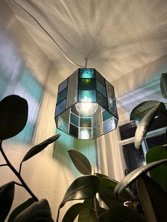 a green lamp hanging from the ceiling next to a potted plant