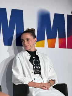 a woman sitting on top of a black chair in front of a wall with the words mmmm