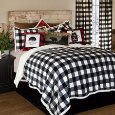 a bed with black and white checkered comforter, pillows and pillow cases on it