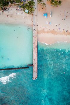 an aerial view of the beach and ocean with people swimming in the water, surrounded by palm trees