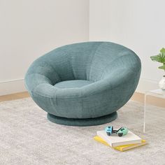 a blue chair sitting on top of a rug next to a book and potted plant