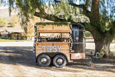 an old fashioned food truck parked under a large tree in front of a house with the word tipsy written on it