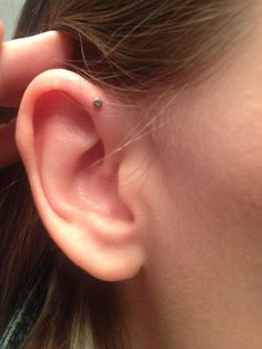 a close up of a person wearing a pair of ear piercings on their ears