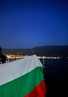 an italian flag is hanging on the side of a boat in the water at night