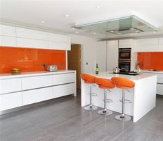 an orange and white kitchen with bar stools