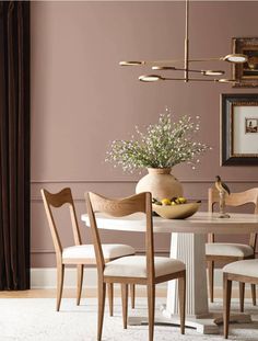 a dining room table with chairs and a vase filled with flowers