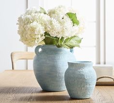 two blue vases with white flowers in them on a table