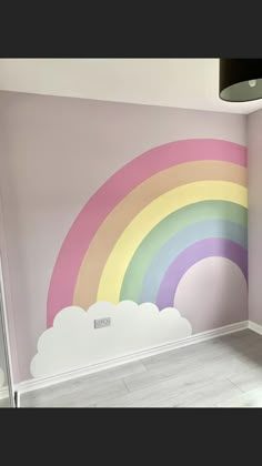 a room with a rainbow painted on the wall next to a window and lamp fixture