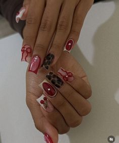 two hands with red and white nail designs on their nails, one holding the other