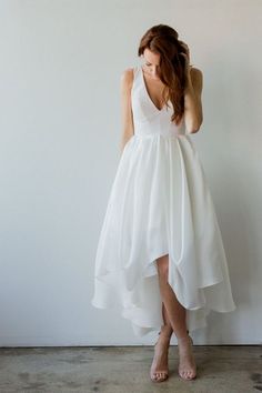 a woman wearing a white dress standing in front of a wall