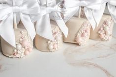 four decorated shoes with bows and pearls on the bottom one is pink, the other is white