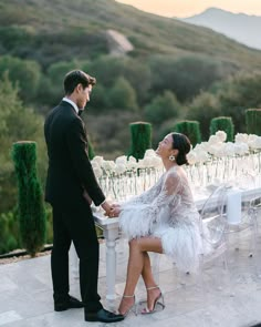 a man and woman standing next to each other at a table with white flowers on it