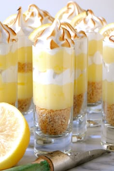 there are many desserts in glass cups with lemon slices on the table next to them