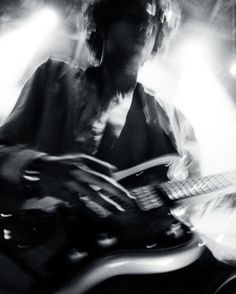 black and white photograph of a man playing an electric guitar in front of spotlights