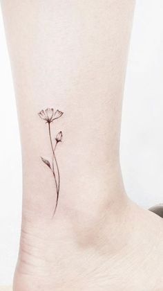 a single flower tattoo on the ankle is shown in black and grey ink, with an outline