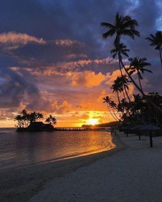 the sun is setting over an island with palm trees