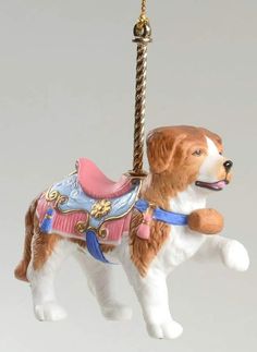 a brown and white dog ornament hanging from a rope with a pink harness