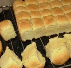 several rolls are cooling on a rack in the oven and one is cut into pieces