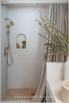 a bathroom with a shower, sink and toilet next to a plant in the corner