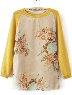 a yellow sweater with flowers on it hanging from a hanger in front of a white wall