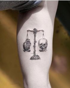 a person with a tattoo on their leg that has a scale and skulls on it