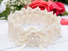 a white lace headband with pearls and bows on it, next to red roses