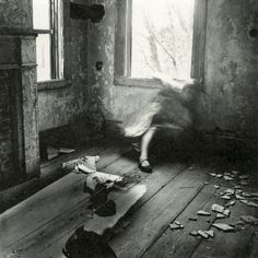 a black and white photo of a person laying on the floor in front of a window