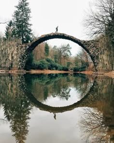 a bridge that is over water with trees in the background and an arabic quote on it