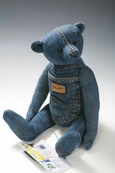 a blue teddy bear with jeans on it's back and the tag in its pocket