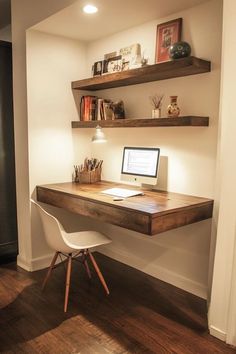 a desk with a computer on top of it and some shelves above the desk behind it