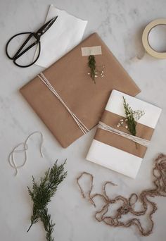 wrapping paper and twine tied together on a marble table with scissors, sprig of rosemary