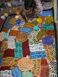 a woman sitting on the floor working on an art project