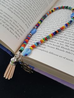 an open book with a tasseled beaded necklace on it's cover