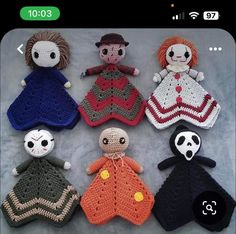 six crocheted dolls are arranged in a circle on a gray surface, one is wearing a red dress and the other has a black hat