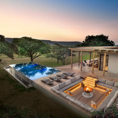 an outdoor living area next to a pool at dusk with fire pit and patio furniture