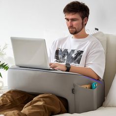 a man sitting on a bed with his laptop in front of him while he is working