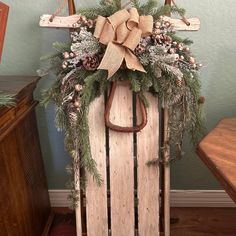 a wooden sled decorated with pine cones, evergreens and a bow on top