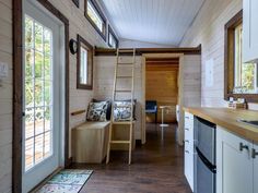 the interior of a tiny cabin with wood floors and walls, windows, and wooden ladders