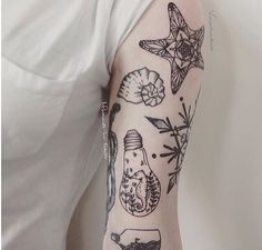 a woman's arm with tattoos on it that include shells, seashells and starfish