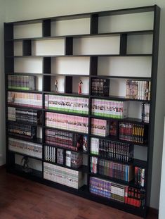 a book shelf filled with lots of books on top of a hard wood floor next to a white wall