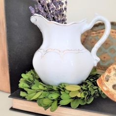 a white pitcher sitting on top of a table next to bread and lavender sprigs