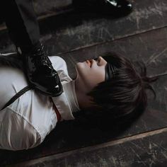 a woman laying on the ground with her head down wearing black shoes and white shirt