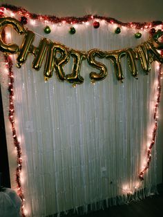 a white backdrop with red and gold balloons that say christmas on it, hanging from the ceiling