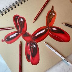 a drawing of a red flower with two crayons on the table next to it