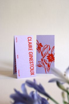 two greeting cards sitting on top of a table next to some purple and white flowers